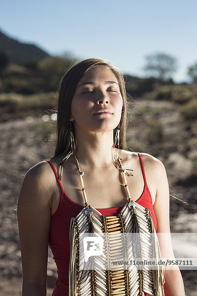 Mixed race woman meditating in remote desert landscape