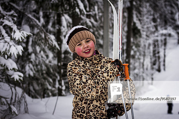 Caucasian girl carrying skis in forest