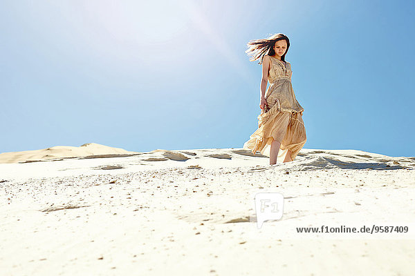 Caucasian woman walking on sand dune hill