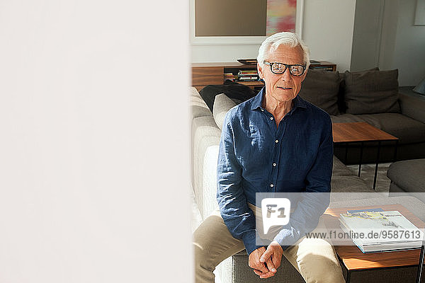 Portrait of senior man wearing glasses sitting in his living room