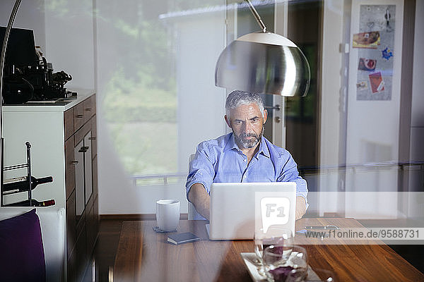 Geschäftsmann bei der Arbeit mit dem Laptop im Home-Office