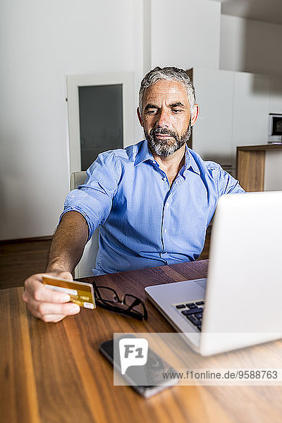 Portrait eines Geschäftsmannes  der seine Kreditkarte für das Online-Banking benutzt.
