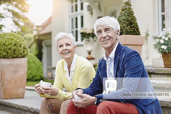 Deutschland  Hessen  Frankfurt  Seniorenpaar auf Stufen sitzend  Tee trinkend