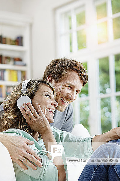Germany  Hesse  Frankfurt  Adult couple at home listening to music