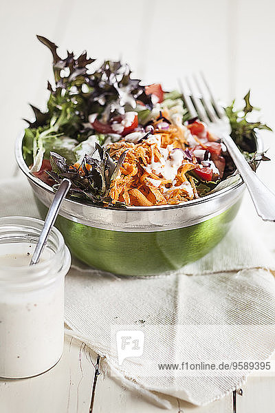 Schüssel mit gemischtem Salat und Glas Joghurtsalatdressing