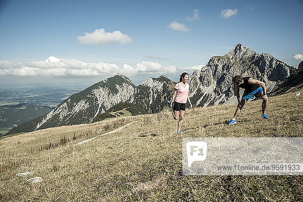 Austria  Tyrol  Tannheim Valley  young couple stretching in mountains