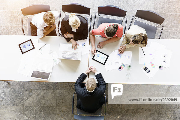 Overhead-Ansicht von Geschäftsleuten  die den Kunden am Schreibtisch im Büro treffen.