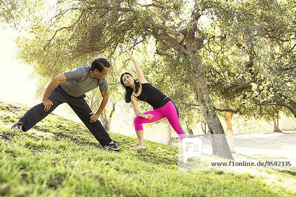 Mature running couple warming up together in park