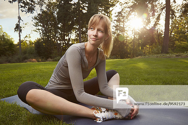 Porträt einer erwachsenen Frau  die Yoga im Park praktiziert.