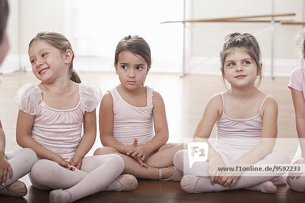 Mädchengruppe in der Ballettschule auf dem Boden sitzend