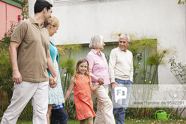 Großfamilie geht Hand in Hand im Garten spazieren