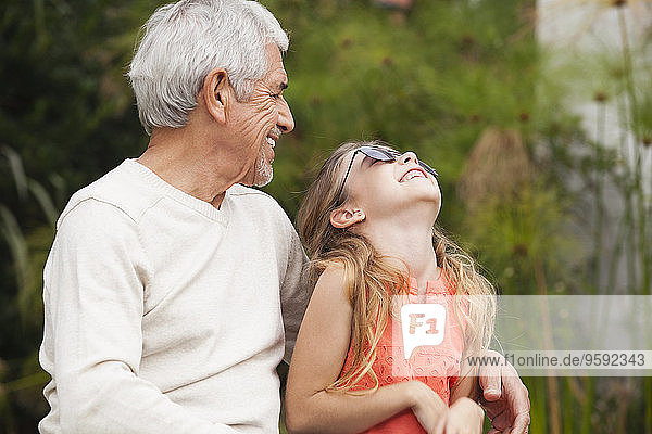 Großvater und glückliche Enkelin mit Sonnenbrille im Freien