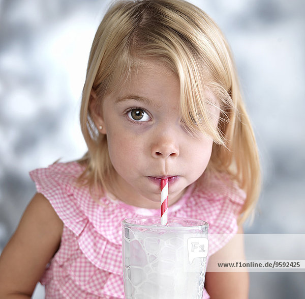 Portrait eines weiblichen Kleinkindes  das Blasen in Milch durch Trinkhalm bläst.