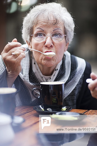 Portrait of senior woman with hot beverage relaxing in a pavement cafe