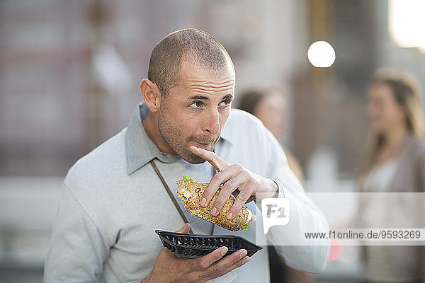 Portrait of businessman eating sandwich at lunchtime