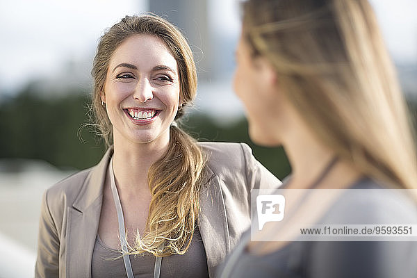 Porträt einer lächelnden Geschäftsfrau  die mit einer anderen kommuniziert.