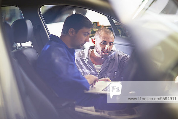 Zwei Automechaniker mit Laptop in der Werkstatt