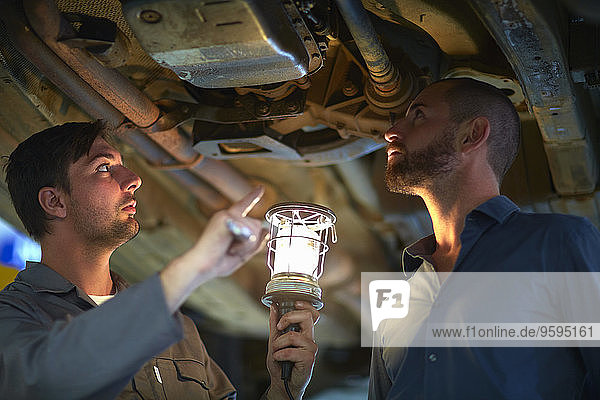 Car mechanic with client in repair garage