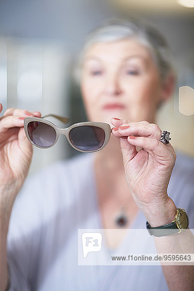 Seniorin beim Optiker beim Anprobieren der Sonnenbrille