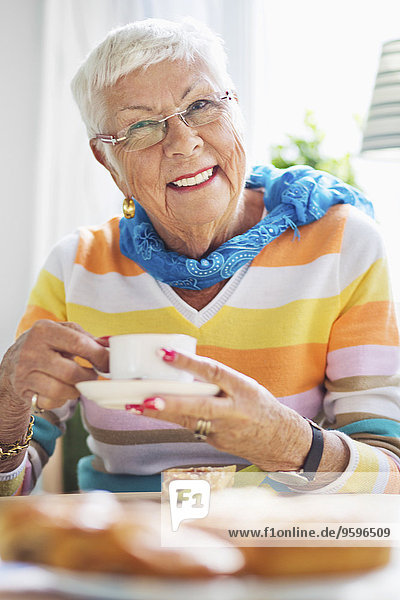 Porträt einer glücklichen Seniorin beim Kaffee im Pflegeheim