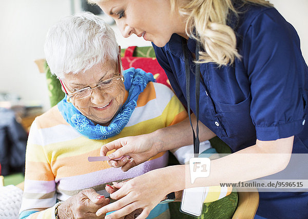 filing senior woman's fingernails at nursing home