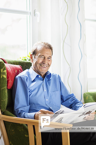 Porträt eines glücklichen älteren Mannes beim Lesen im Pflegeheim