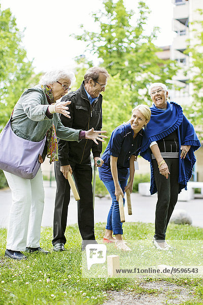 Happy female playing kubb game with senior people at park