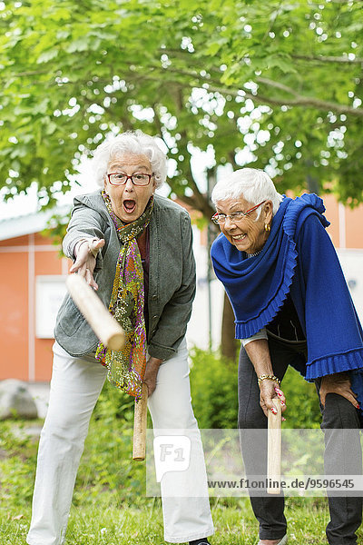 Aufgeregte Senioren genießen Kubb-Spiel im Park