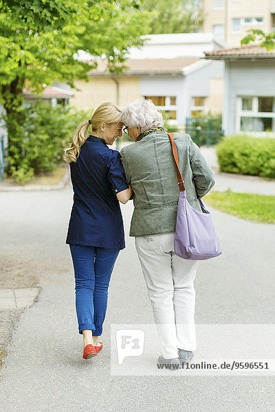 Durchgehende Rückansicht der zärtlichen Frau und Seniorin auf der Straße