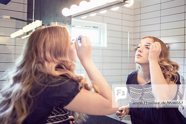 Junge Frau mit Mascara vor dem Badezimmerspiegel