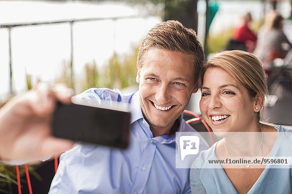 Lächelnde Geschäftsleute  die Selfie durch Smartphone im Cafe nehmen