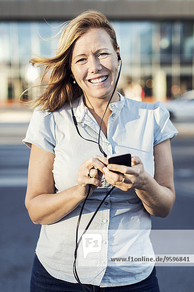 Portrait of happy businesswoman using mobile phone outdoors
