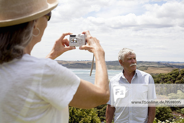 Ehefrau fotografiert Ehemann  Ozean im Hintergrund  Raglan  Neuseeland