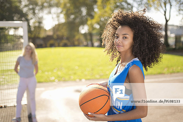 Portrait of young woman holding basketball
