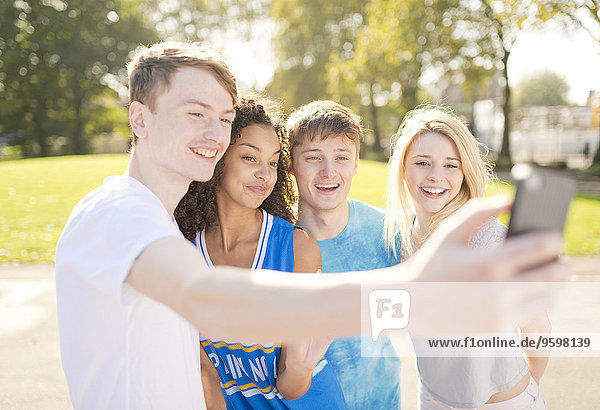 Vier junge erwachsene Basketballspieler posieren für Smartphone Selfie