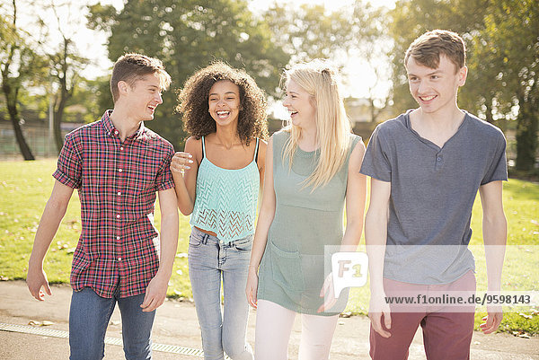 Vier junge erwachsene Freunde beim Spaziergang im Park
