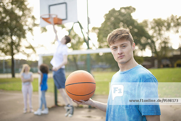 Porträt eines jungen Basketballspielers  der Basketball hält