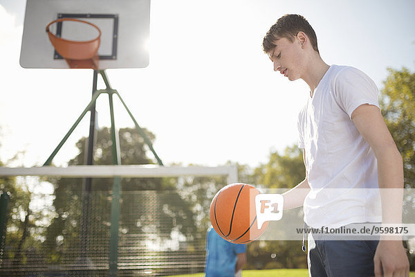 Junger Basketballspieler auf dem Platz mit Basketball
