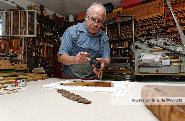 Senior Mann repariert zerbrechlichen Buchrücken in traditioneller Buchbinderei