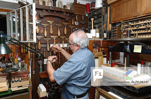 Senior Mann bei der Auswahl der Werkzeuge in der traditionellen Buchbinderei
