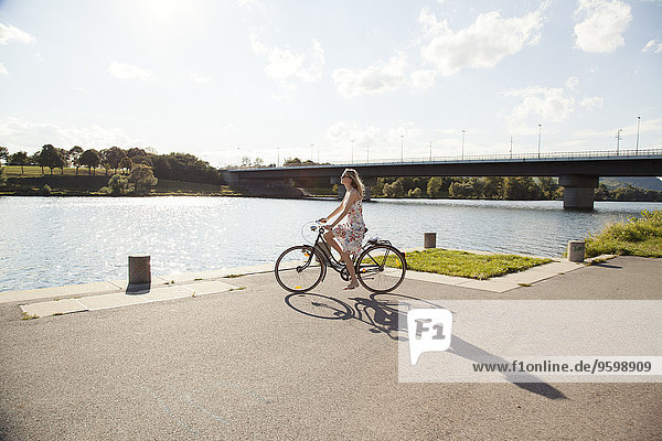 Junge Frau beim Radfahren am Flussufer  Donauinsel  Wien  Österreich