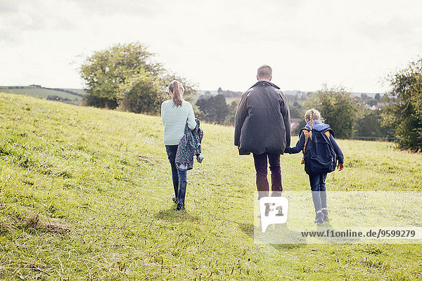 Father and daughters walking in field