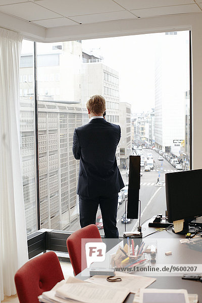 Businessman on the phone in office looking through window
