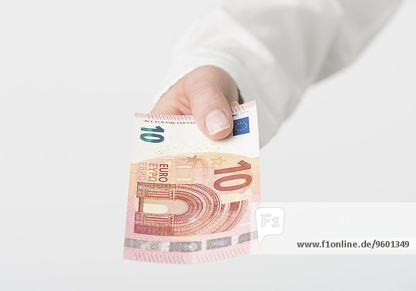 Frauenhand hält Zehn-Euro Geldschein nach vorne