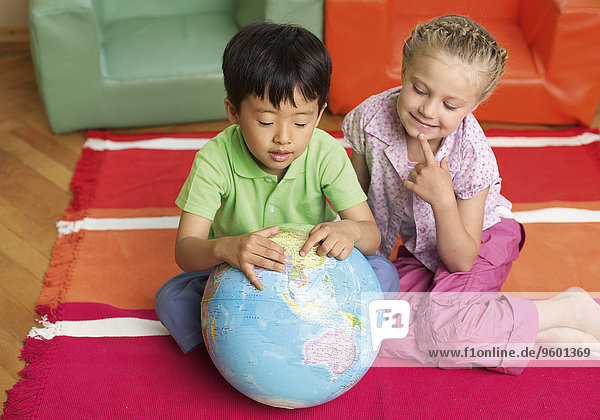 Zwei Kinder betrachten einen Globus