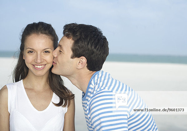 Junger Mann küsst junge Frau am Strand