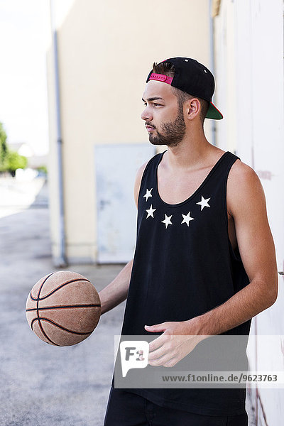 Young man with basketball wearing basecap
