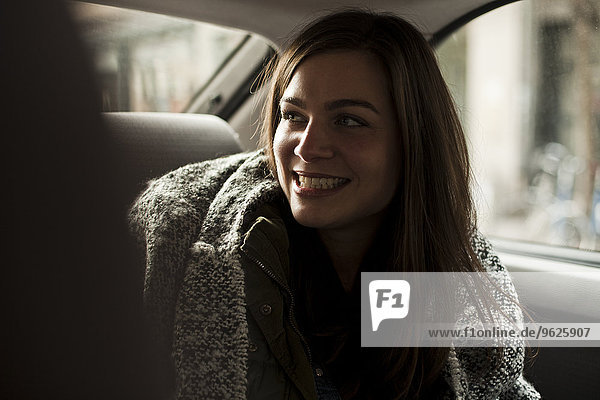 Porträt einer lächelnden Frau auf dem Rücksitz eines Autos