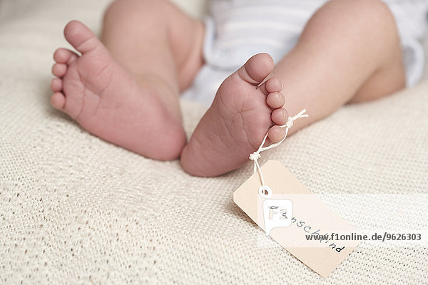 Babyfüße mit'geplantes Kind' auf Kartonschild geschrieben