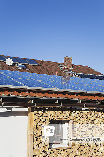 Deutschland  Weisenheim am Berg  Sonnenkollektoren auf dem Dach und Lagerung von Brennholz unter der Veranda eines Hauses